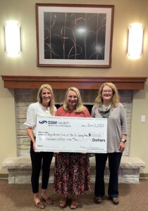 Three people holding a big check