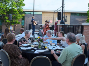 A large group of people sitting around a table outside