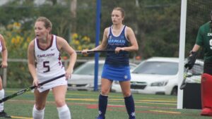 Two women playing field hockey