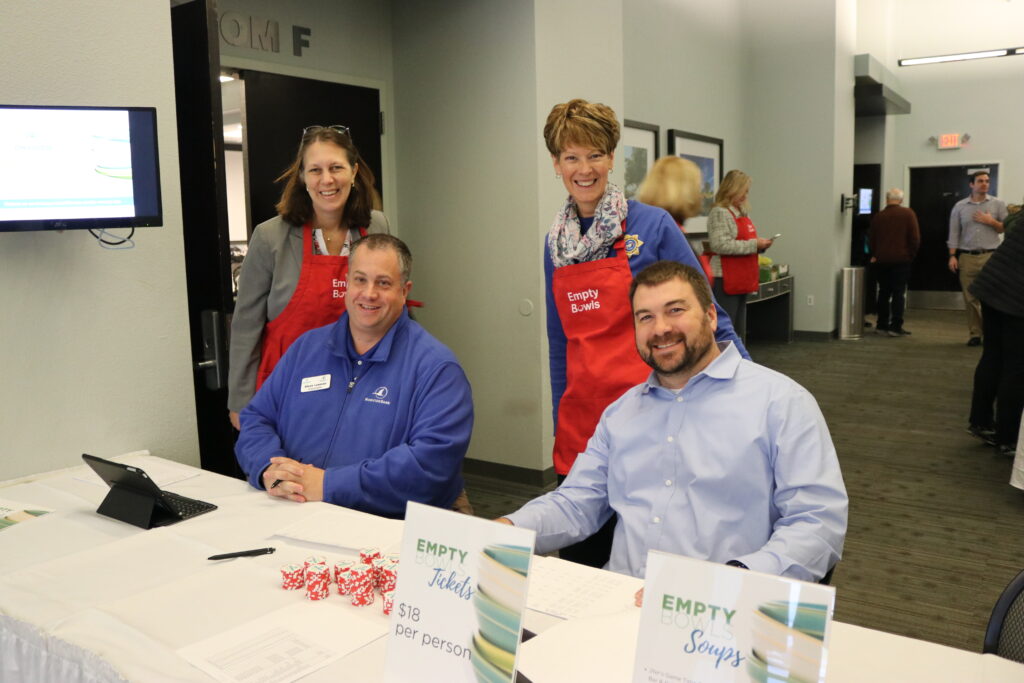 Four people. Two sitting and two with aprons.