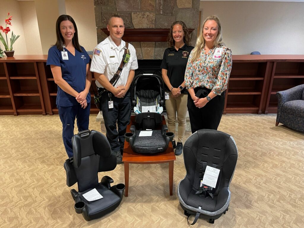 Four people standing with four car seats