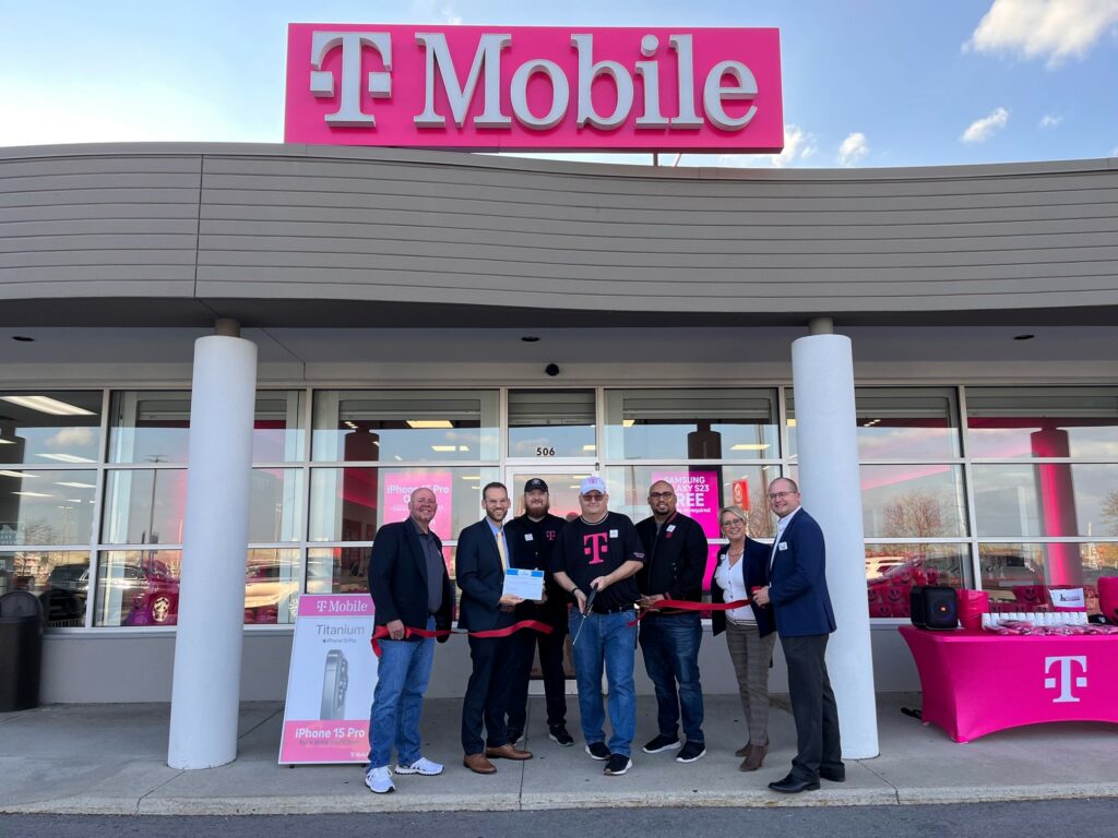 Seven people standing in front of a store for a ribbon cutting