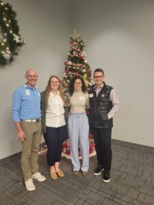 Four people standing in front of a Christmas tree