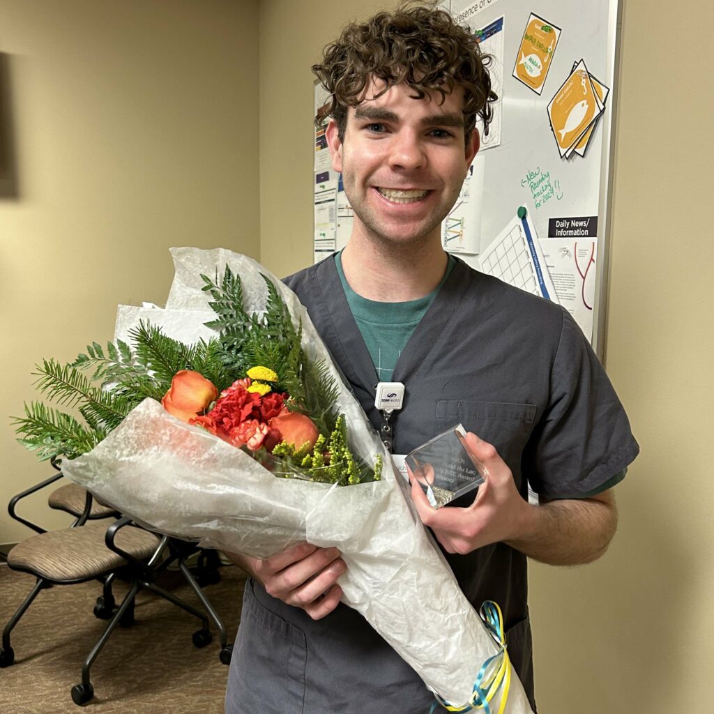 Male nurse holding flowers and an award