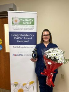A nurse holding flowers and an award