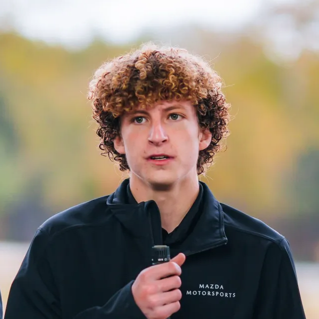 A young man with curly hair holding a mic
