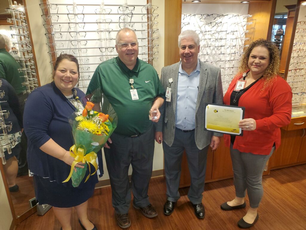 Two women and two men with flowers and an award
