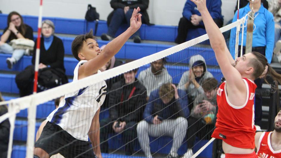 Two men playing college volleyball
