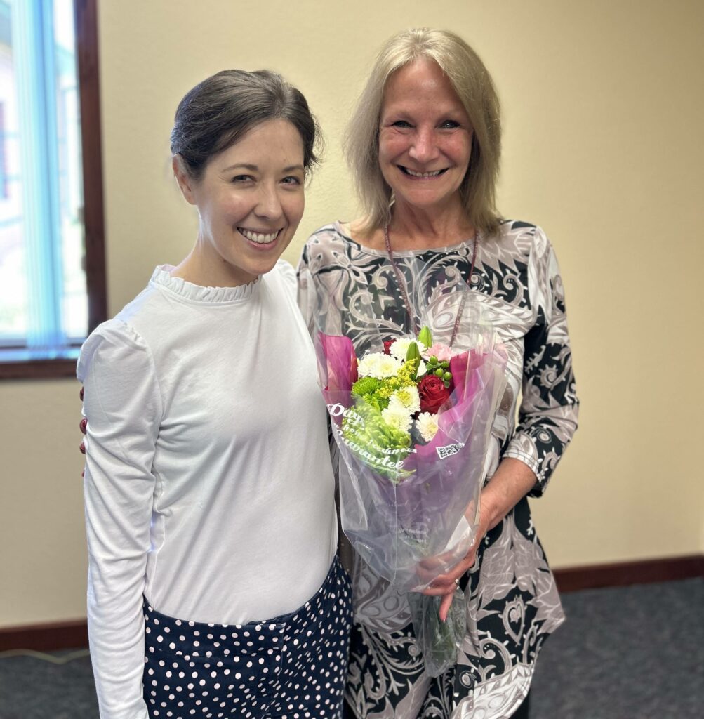 Two women, with one holding flowers