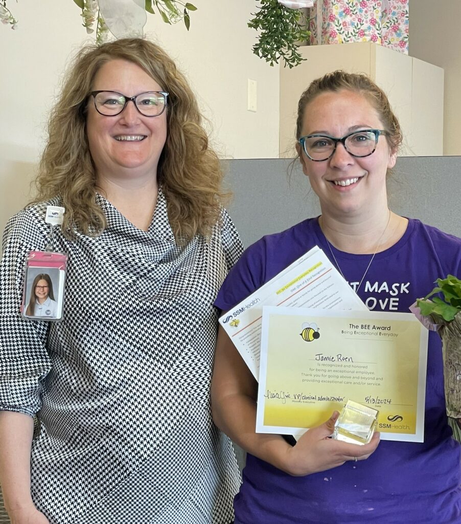 Two females with one holding an award