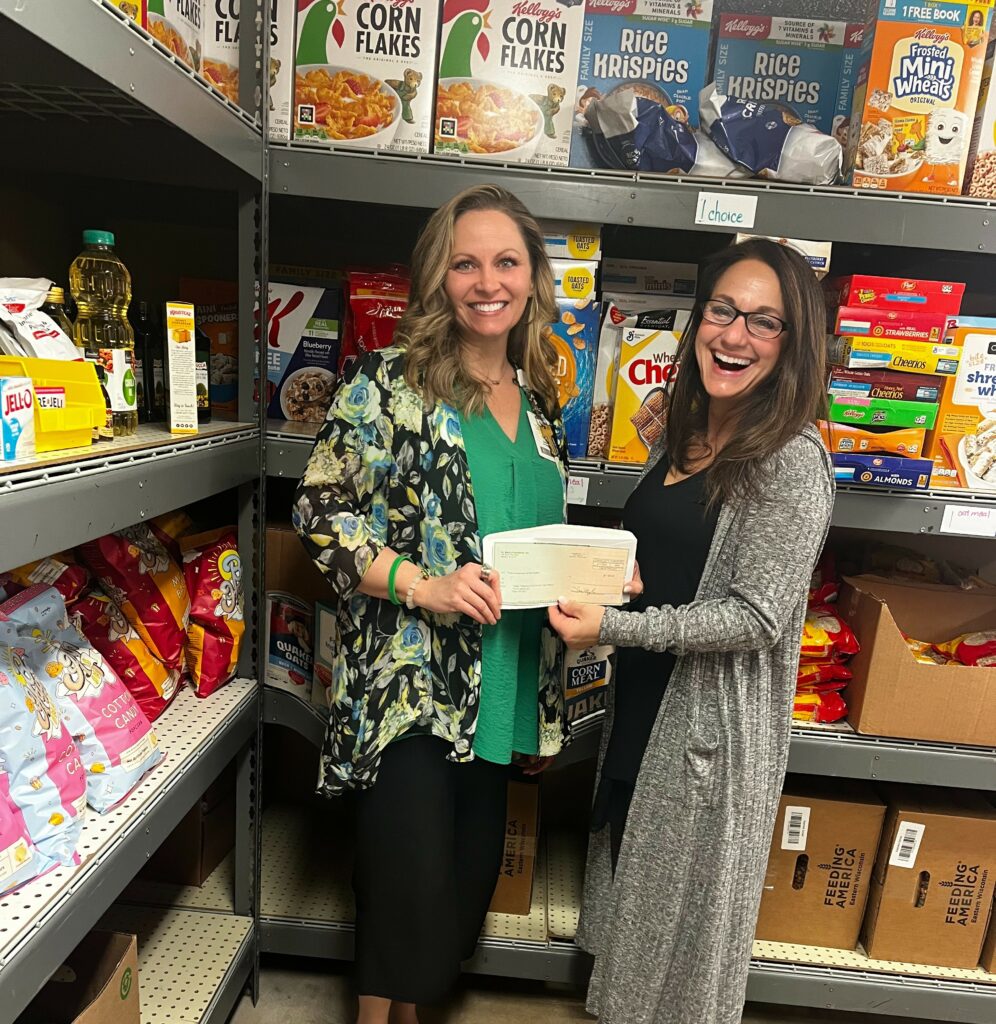 Two women in a food bank with a check