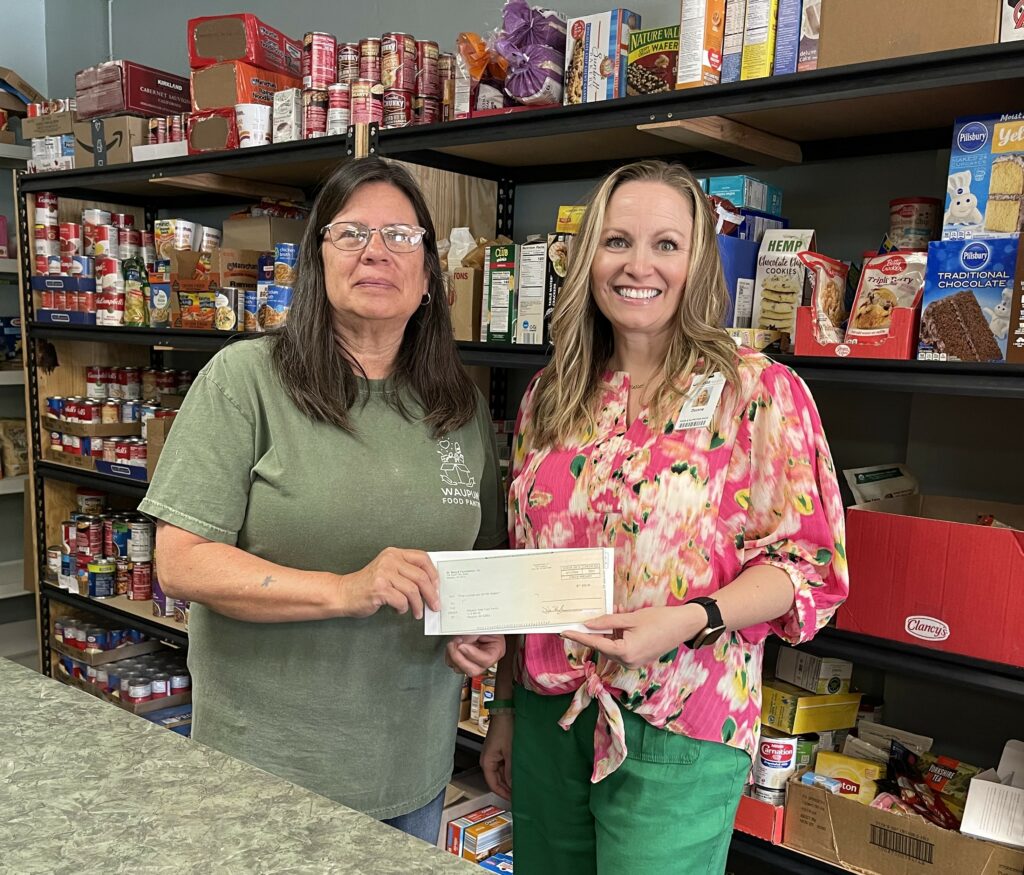 Two women in a food pantry with a check