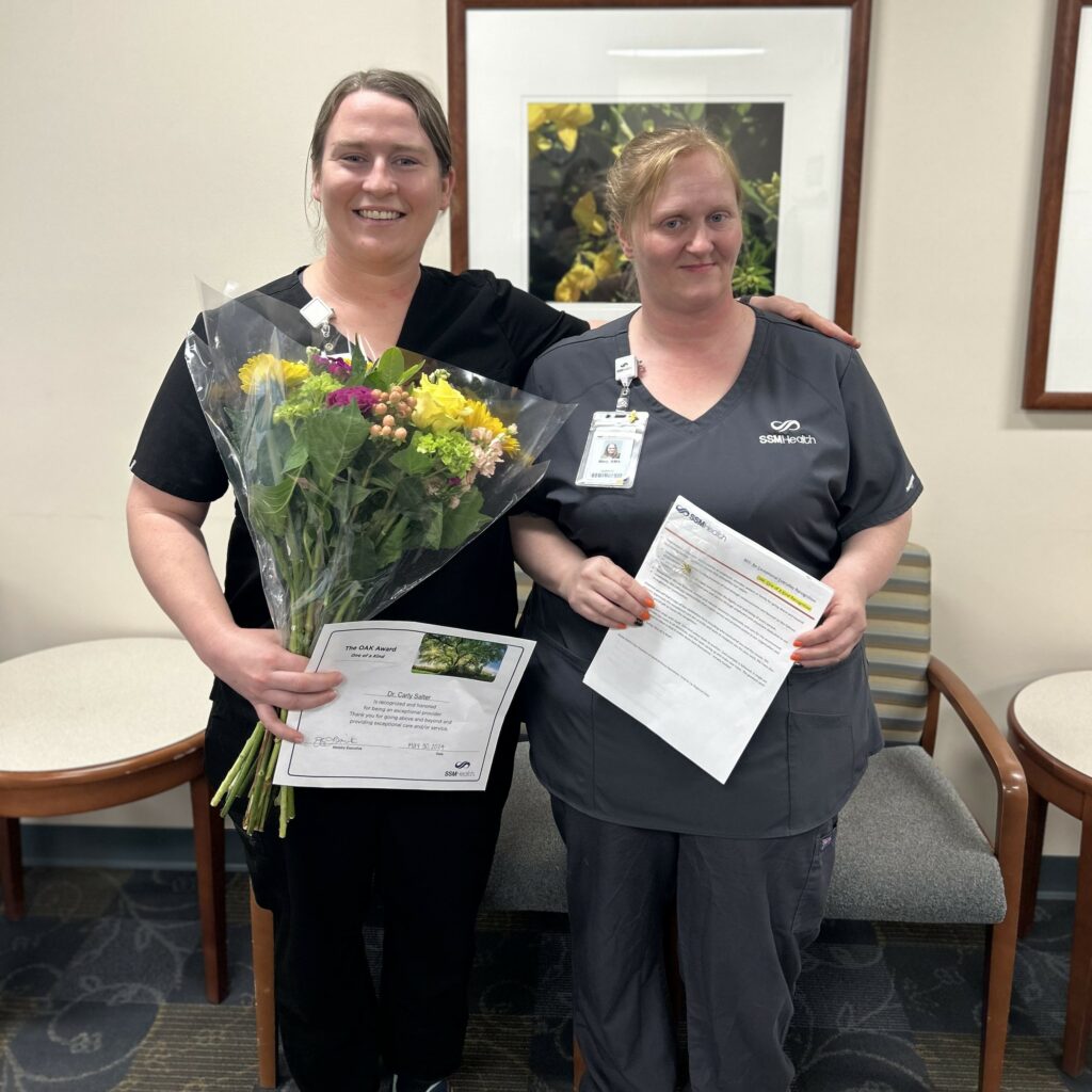 Two women with flowers and an award