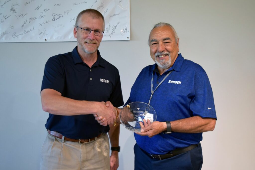 Two men with one holding an award
