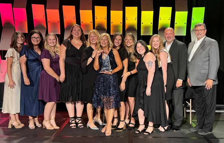 A large group of people on stage with an award