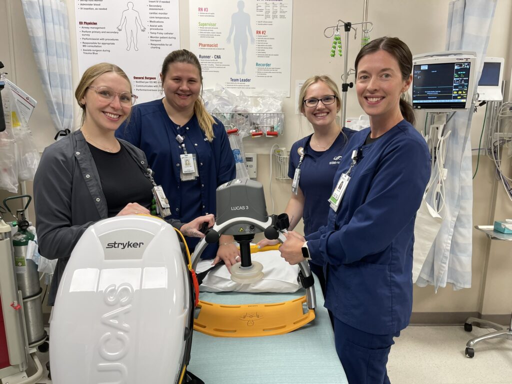 Four medical professionals by a piece of equipment