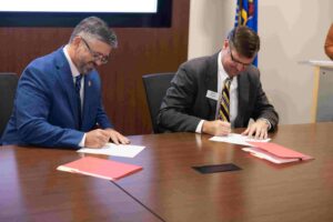Two men sitting at a table signing documents