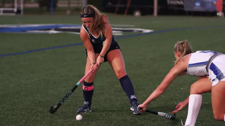 Women playing field hockey