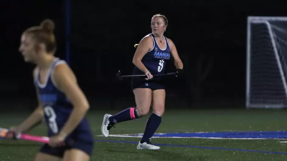 Women playing field hockey
