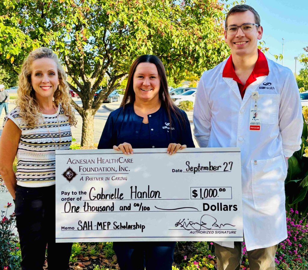 Three people with a big check