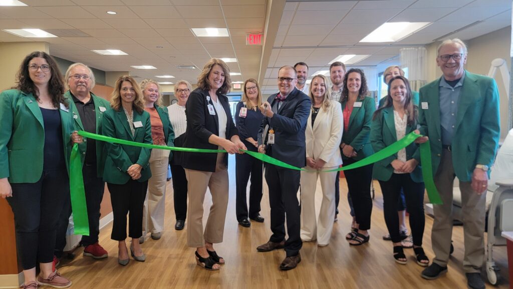 A large group of people inside for a ribbon cutting.