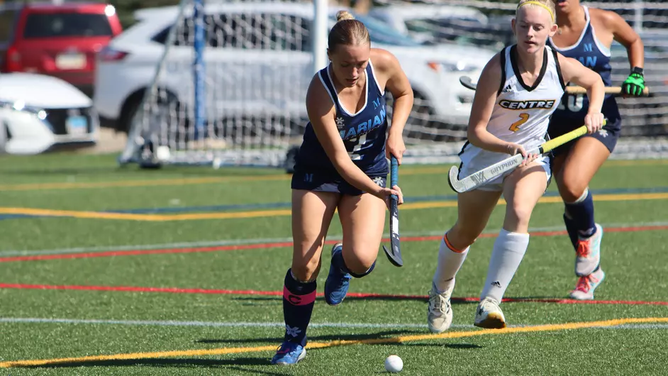 Women playing college field hockey