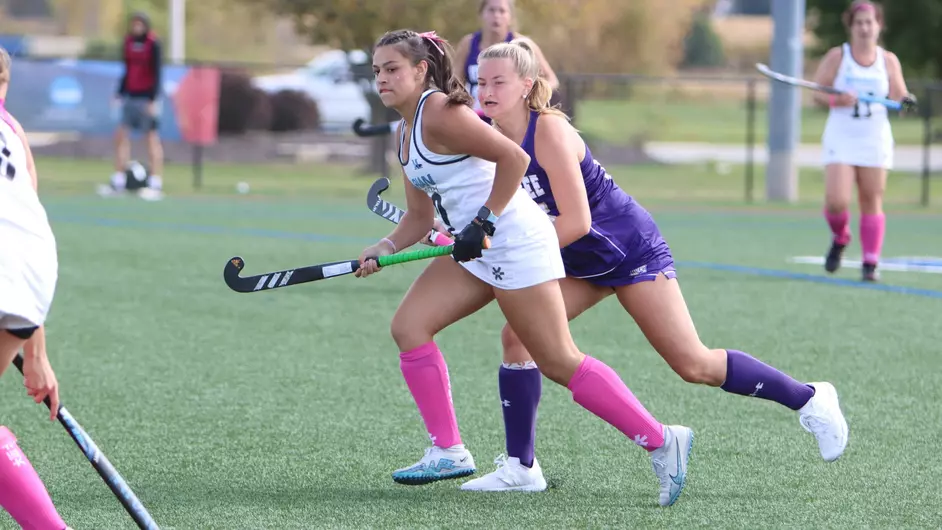 Women playing college field hockey