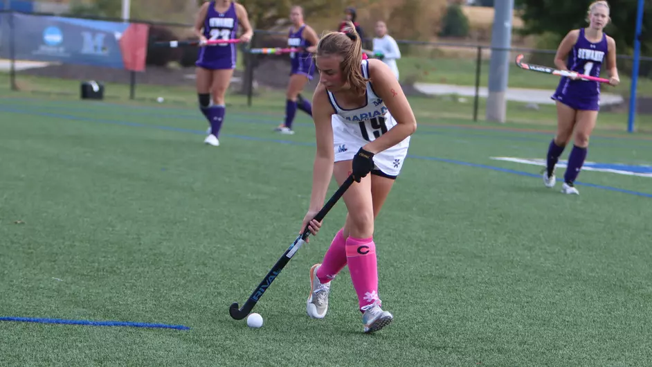 Women playing college field hockey