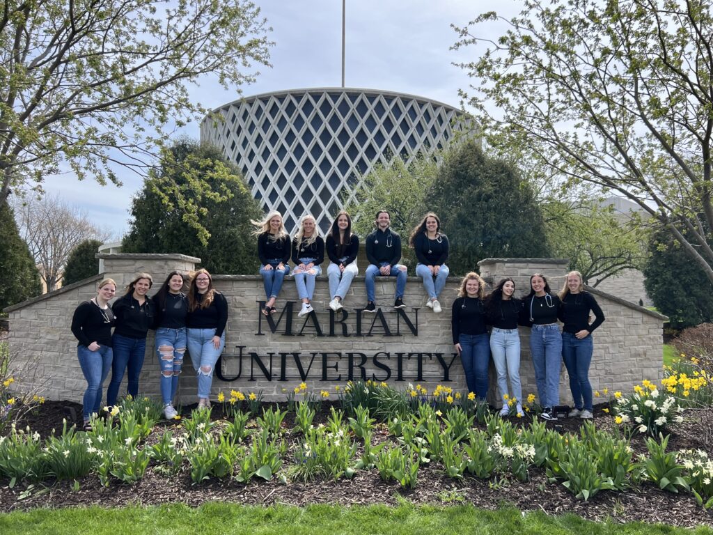 A group of nursing students outside by a sign