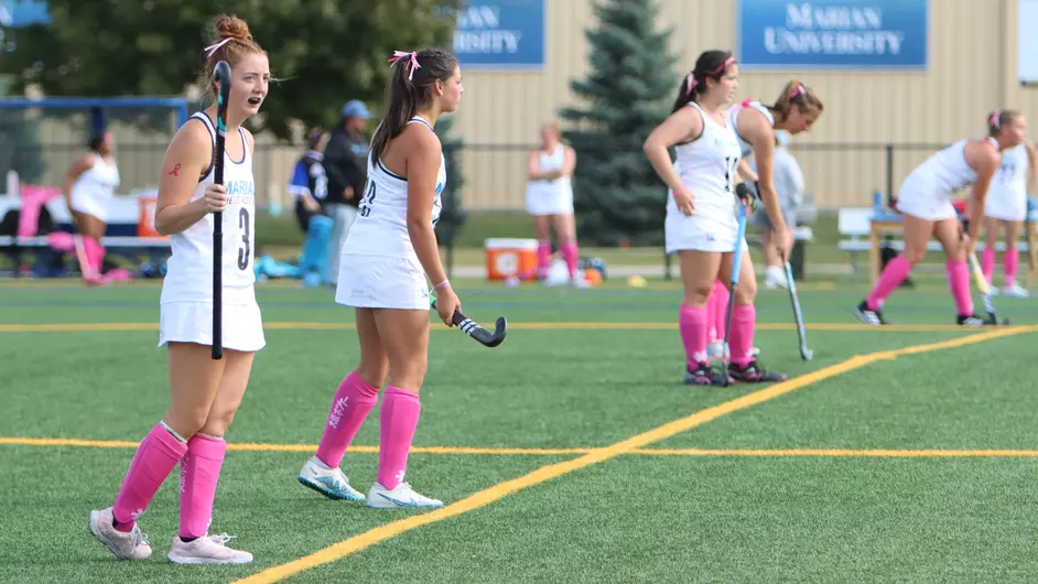 Women playing college field hockey