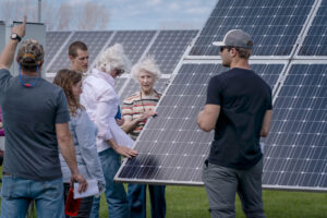 A group of people outside by a solar panel