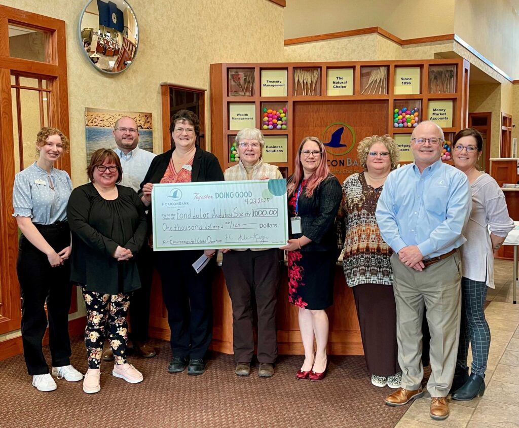 A large group of people holding a big check