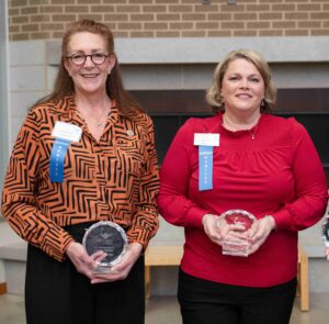 Two women holding awards
