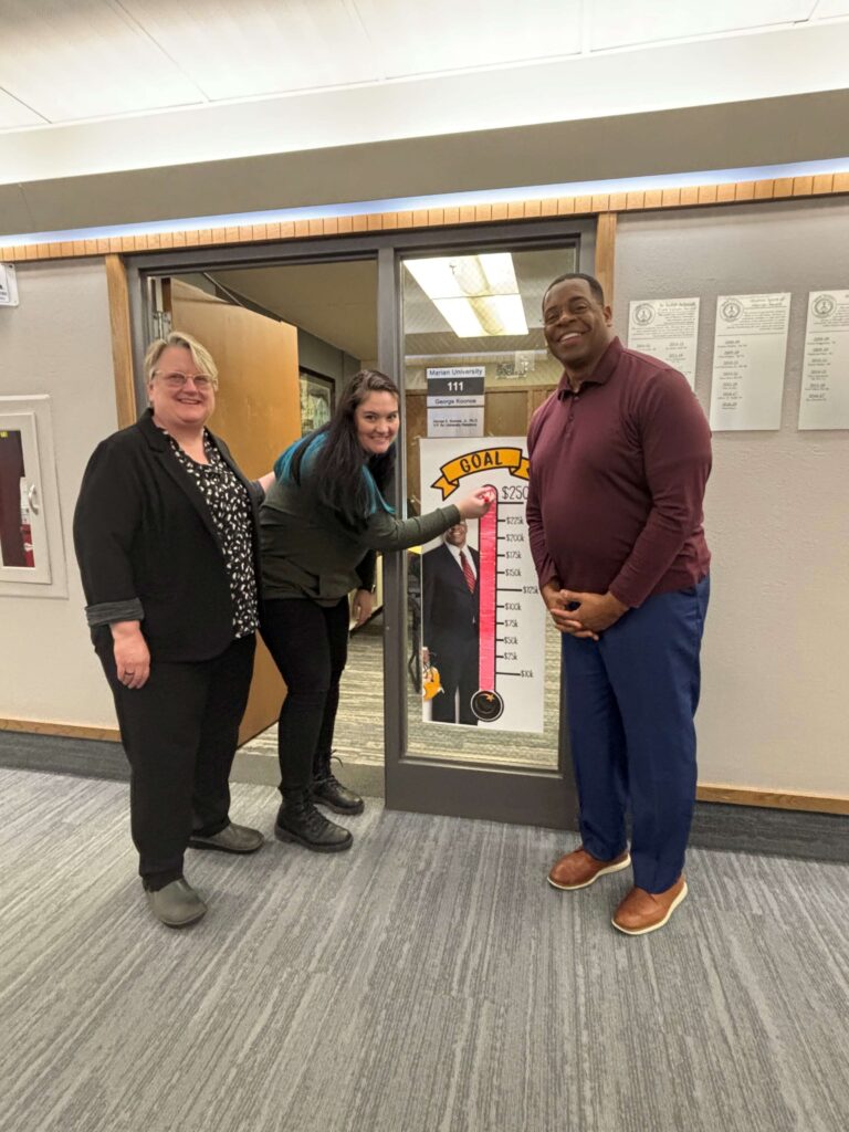 Two women and a man outside a classroom door