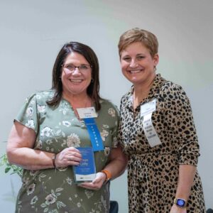Two women, one holding an award