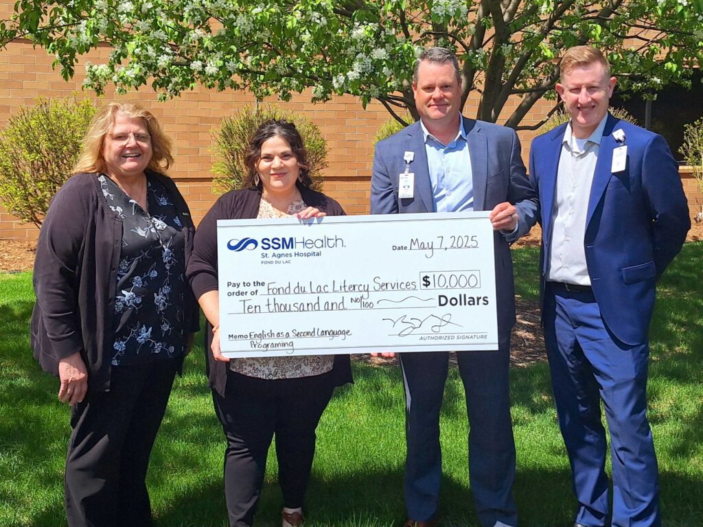Four people standing outside with a big check