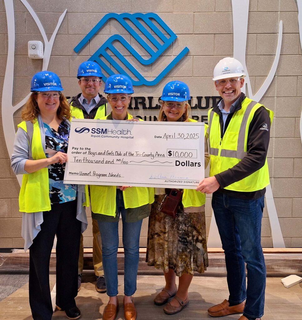 A group of five people in hard hats holding a big check