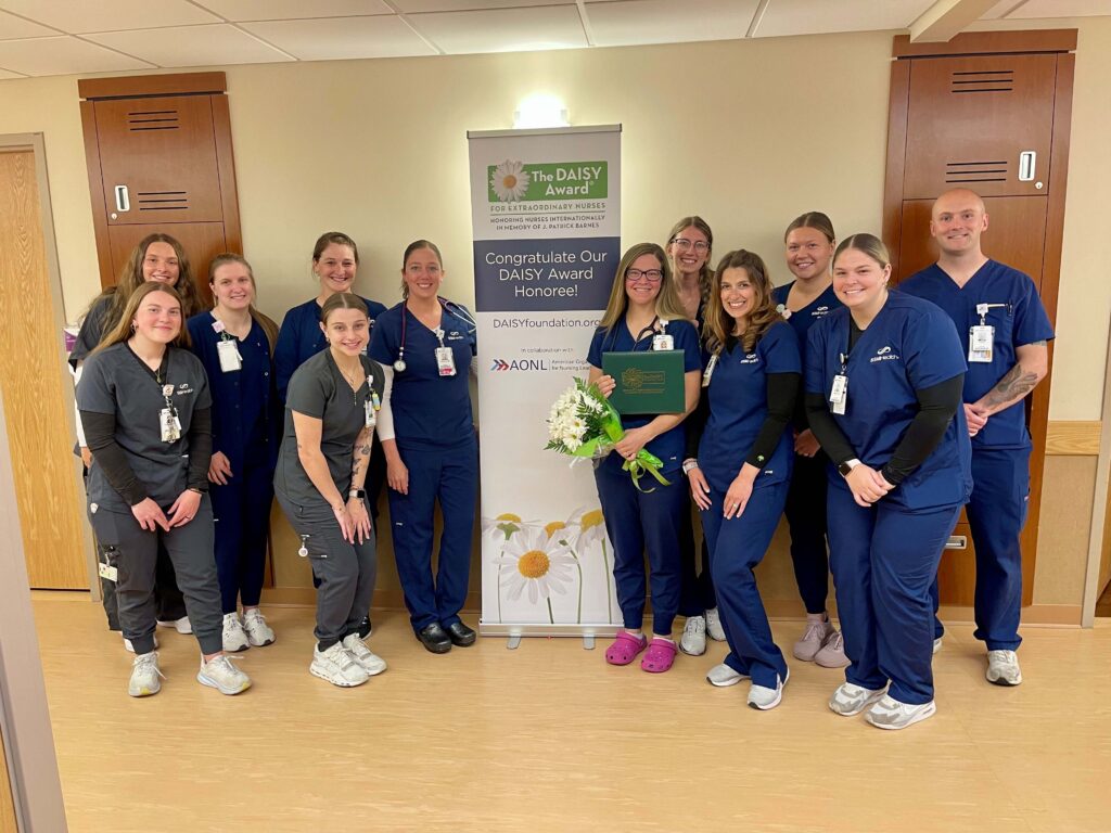 A large group of medical professionals gathered award a daisy award winner