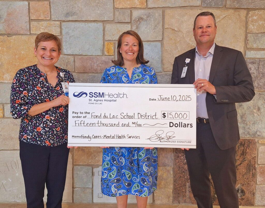 Three people holding a big check