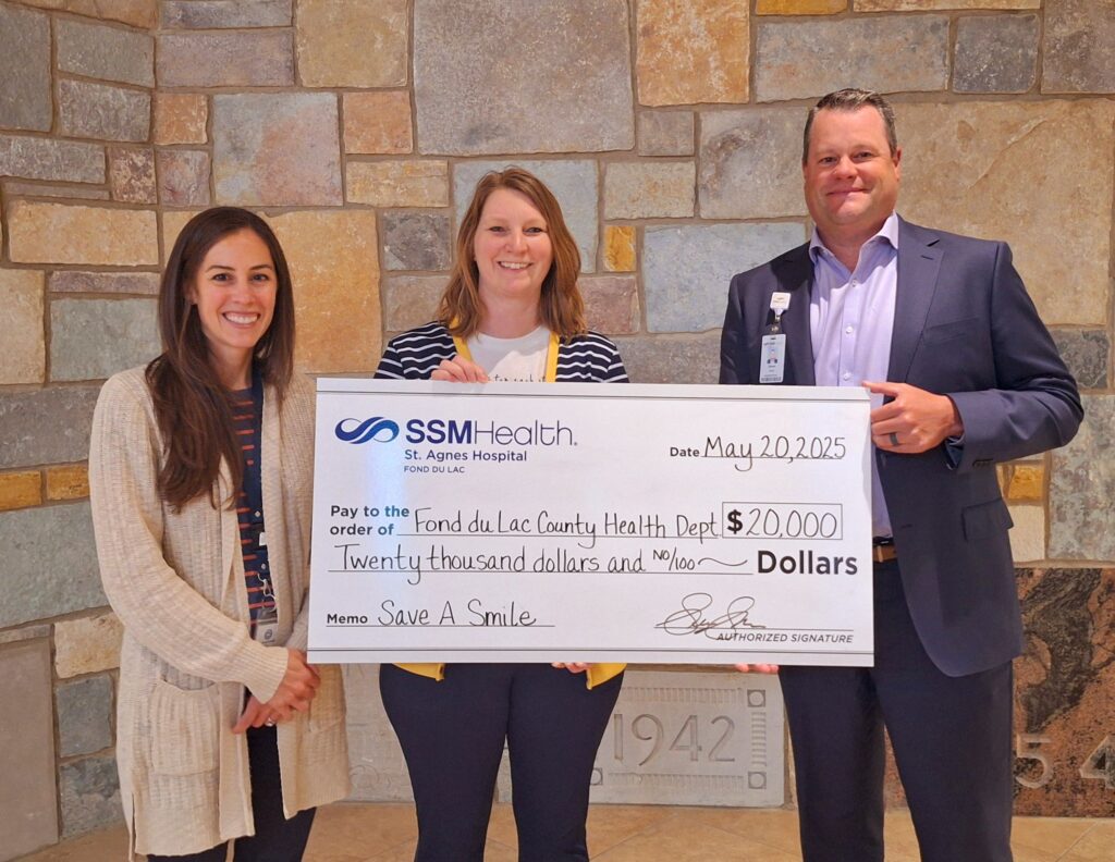 Three people holding a big check