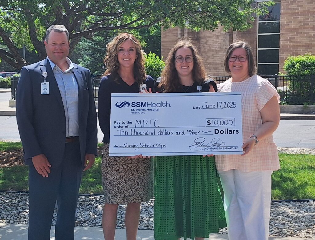 Four people standing outside with a big check
