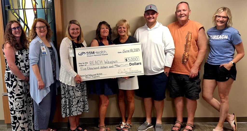 Eight people standing with a big check