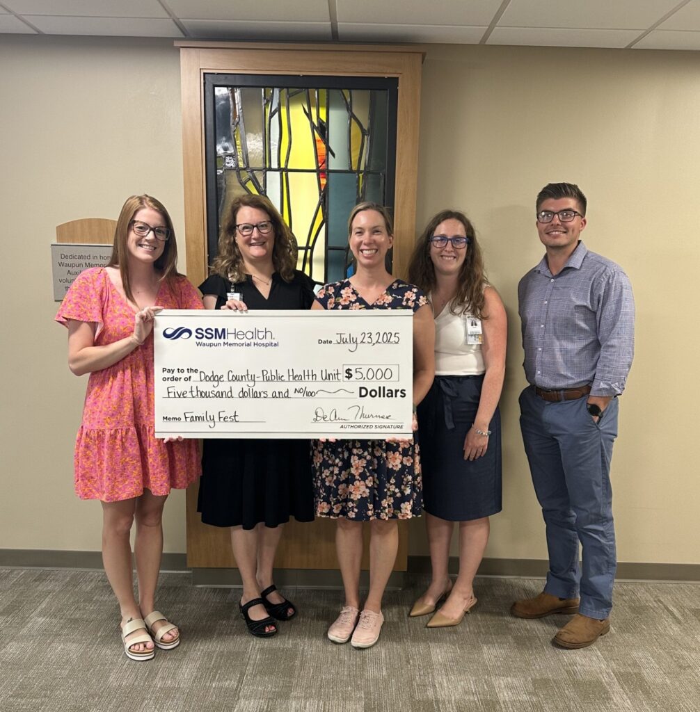 Five people inside holding a big check