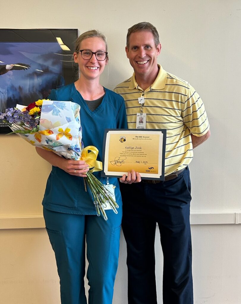 A man and a woman holding flowers and a certificate