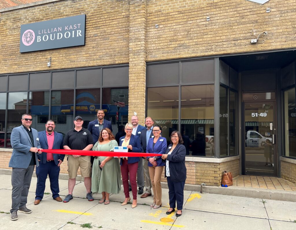 A group of ten people outside for a ribbon cutting.