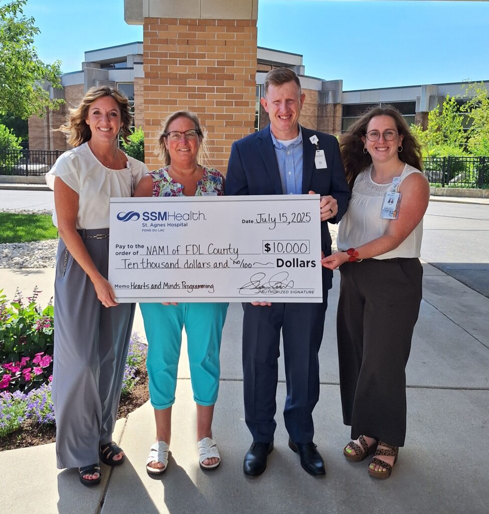 Four people standing outside with a big check