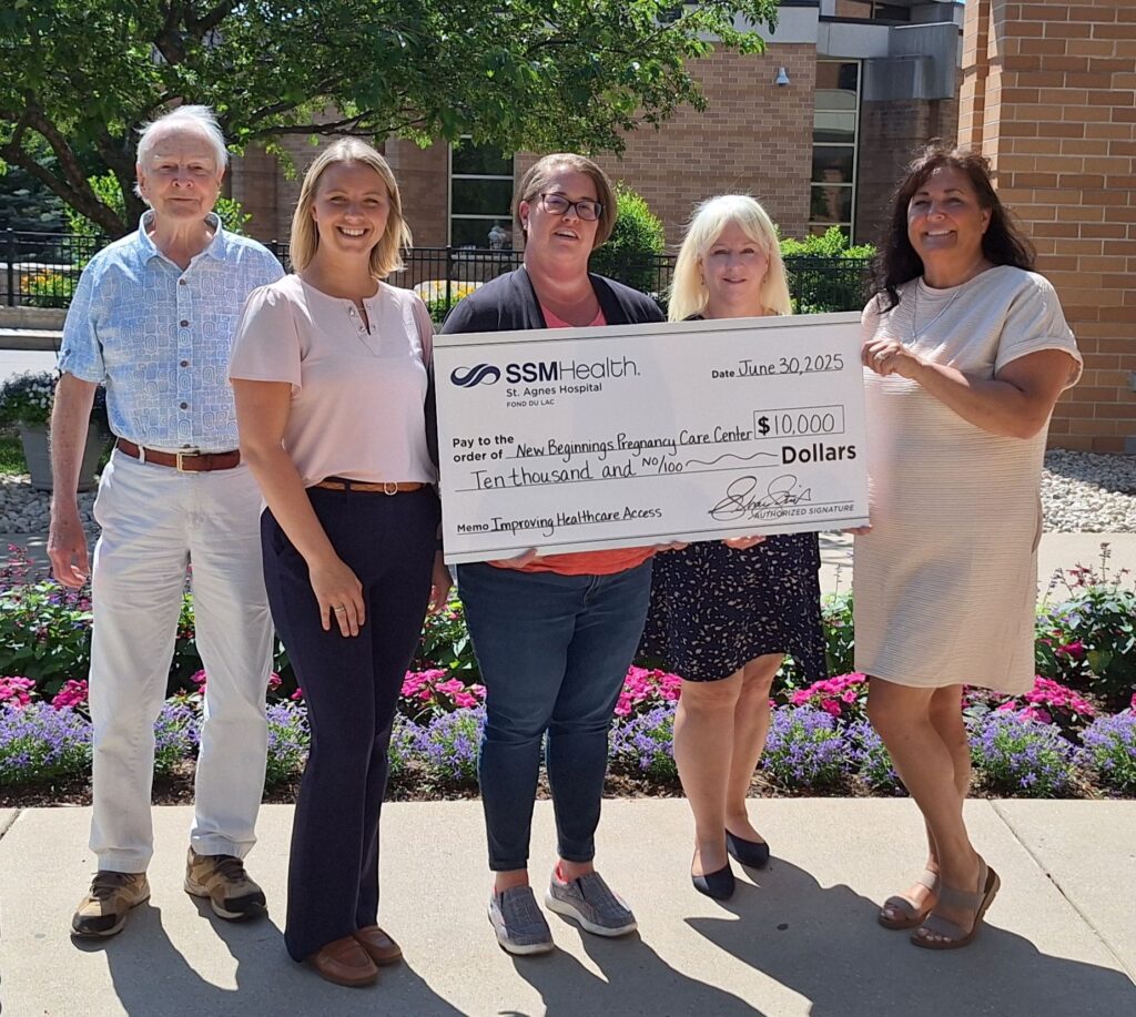 Five people standing outside holding a big check