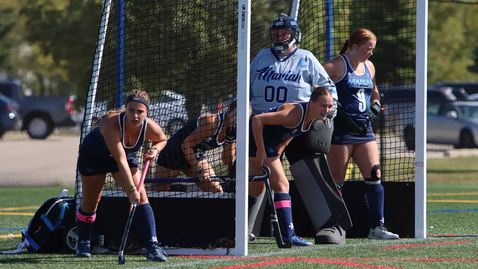 Women playing college field hockey