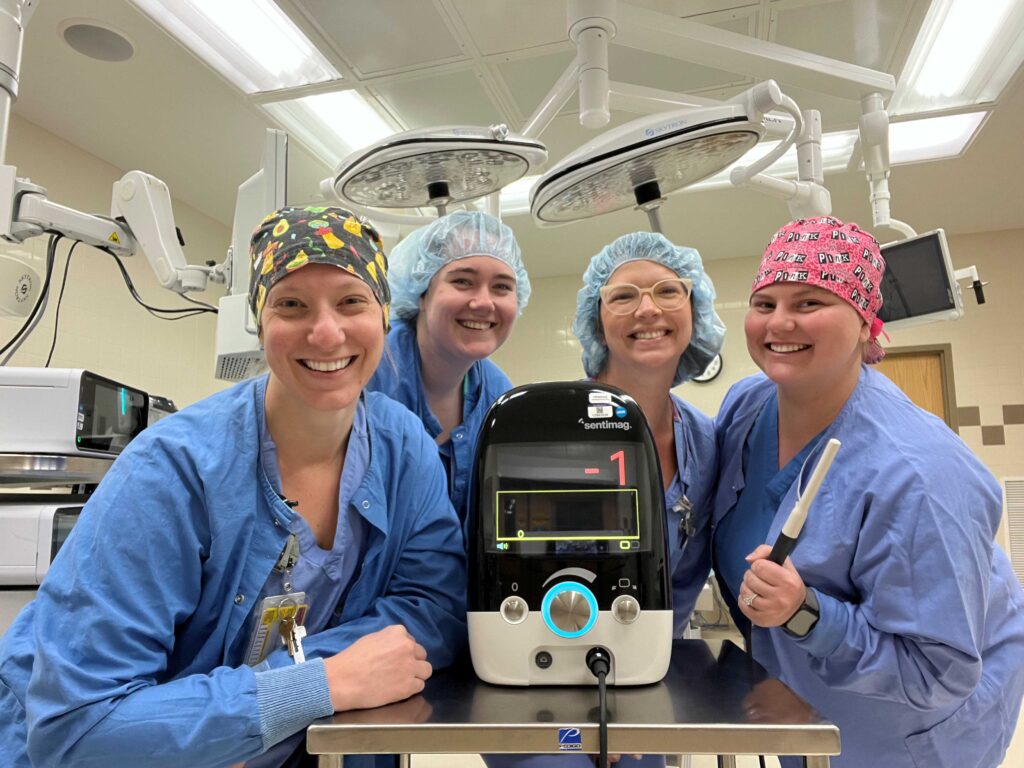 4 medical professionals by a piece of equipment