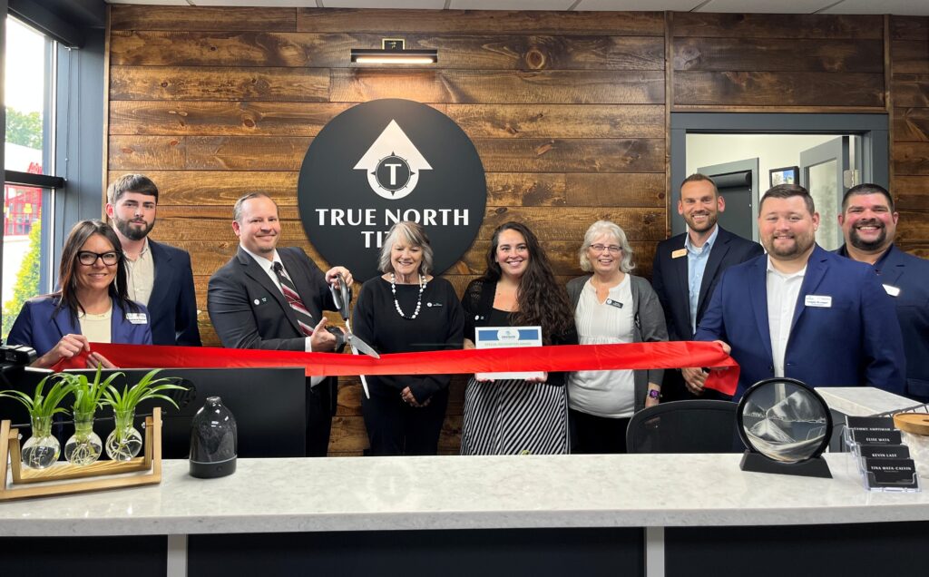 A group of nine people inside for a ribbon cutting
